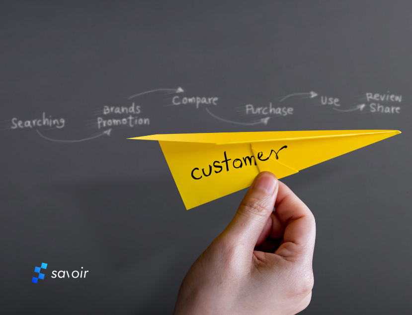 Hand holding a paper airplane with 'customer' written on it, against a chalkboard with a customer journey map sketched in white.